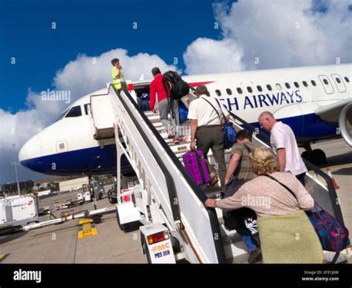 airplane passengers filing down the airplane aisle while boarding