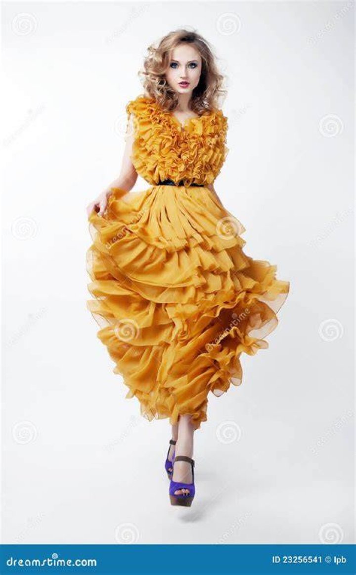 Model in a yellow dress walking down a white runway