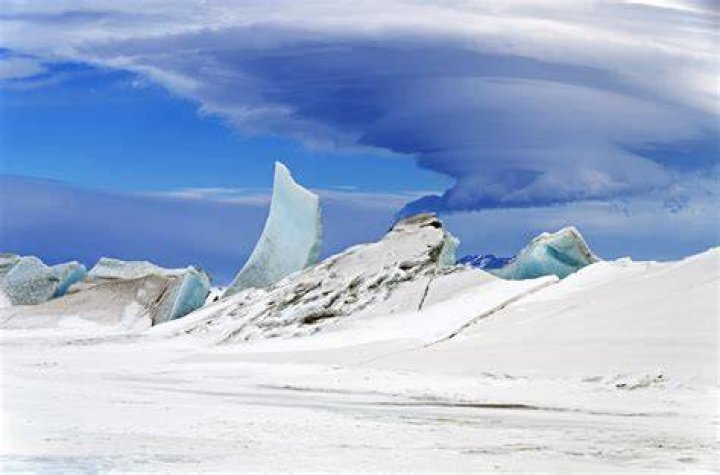 mountain behind blue ice glacier and green trees