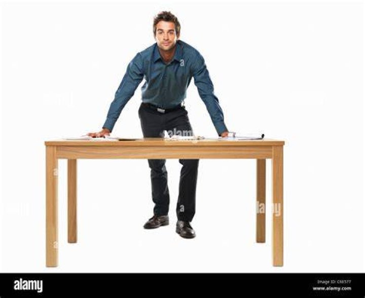 person behind a table holding iPhone with tea and pastry on a table