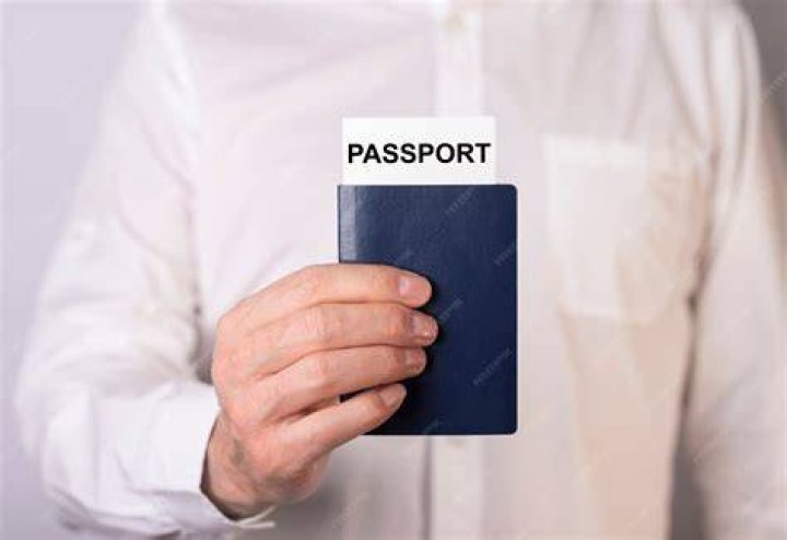 person holding up passport full of cash