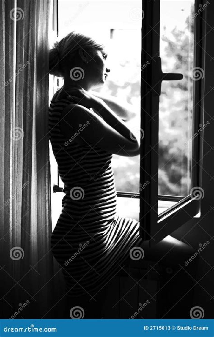 woman standing by window and opening curtains