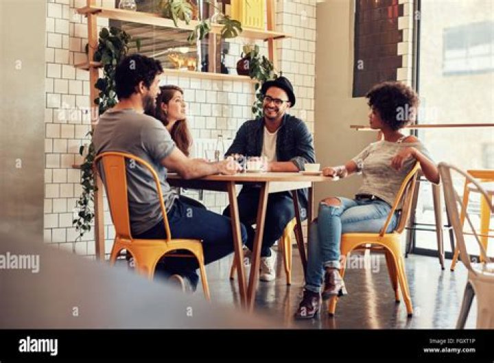 Young people sitting around a table talking